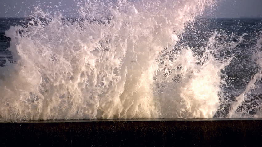 Sea. Surf waves break on the granite fence. Spray soar into the air and sparkle