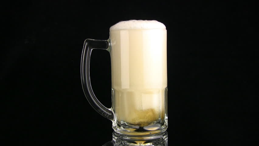 The beer from the mug, filled up to edges, is poured slow through edge. A black