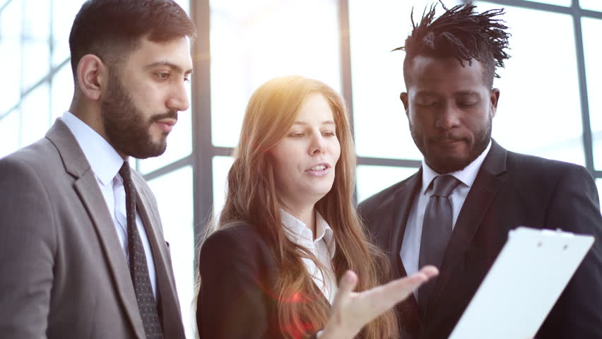 standing in a modern office corridor, one of the employees points to a clause in the contract