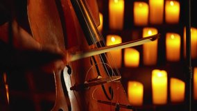 Close-up of a musician playing a bow on a stringed instrument. Candles burning in the background. The light of candles creates a serene and intimate atmosphere of the concert. - Powered by Shutterstock - Get 15% off with code: PIKWIZARD15