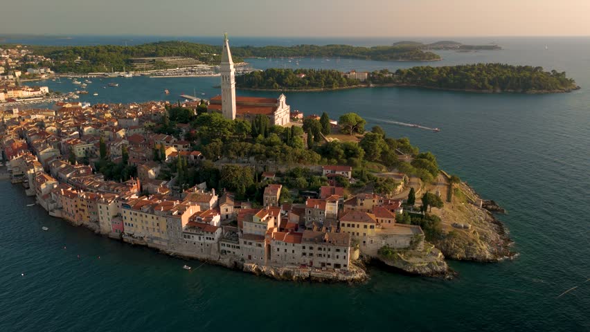 Experience the breathtaking views of Rovinj Croatia picturesque coastline as the sun sets, casting a warm glow over charming buildings and tranquil waters.
