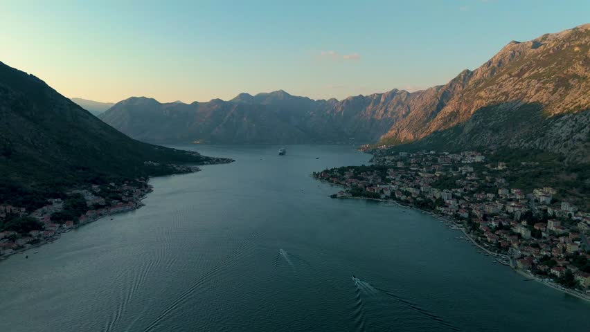 Witness the stunning panorama of Kotor Bay as the sun sets behind the majestic mountains, casting warm hues over the tranquil waters. Nature