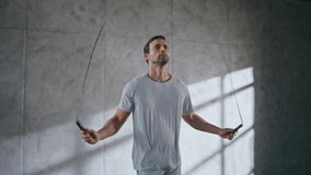Closeup serious fitness man jumping in loft sport club. Young male athlete using skipping rope feeling motivated at empty light room. Determinate strong guy training alone. Active lifestyle concept  - Powered by Shutterstock - Get 15% off with code: PIKWIZARD15