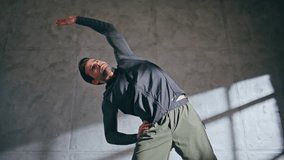 Fitness guy stretching body in loft gym low angle. Motivated athletic man having workout at wellness training. Male athlete in sportswear preparing sport exercise. Brunette fit trainer warm up muscle - Powered by Shutterstock - Get 15% off with code: PIKWIZARD15