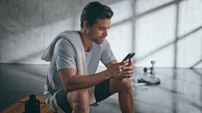Smiling sportsman looking mobile phone after morning training home closeup. Fitness tired guy holding cellphone messaging after exercising. Athletic man browsing workout app on smartphone at bench  - Powered by Shutterstock - Get 15% off with code: PIKWIZARD15