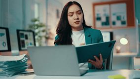 Asian businesswoman works late in her office, feeling stressed and overwhelmed by her heavy workload. The pressure of deadlines and multitasking contributes to her anxiety and frustration - Powered by Shutterstock - Get 15% off with code: PIKWIZARD15