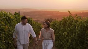 Happy couple dating outdoors in nature walking through vineyards holding hands in golden hour. Young woman and man having picnic relax enjoy time together during grapes harvest season - Powered by Shutterstock - Get 15% off with code: PIKWIZARD15