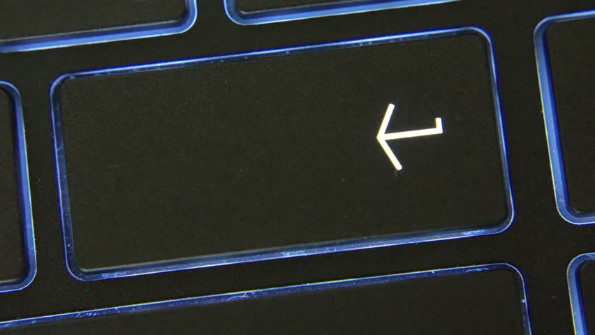 Close-up of index finger pressing enter key on black backlit keyboard