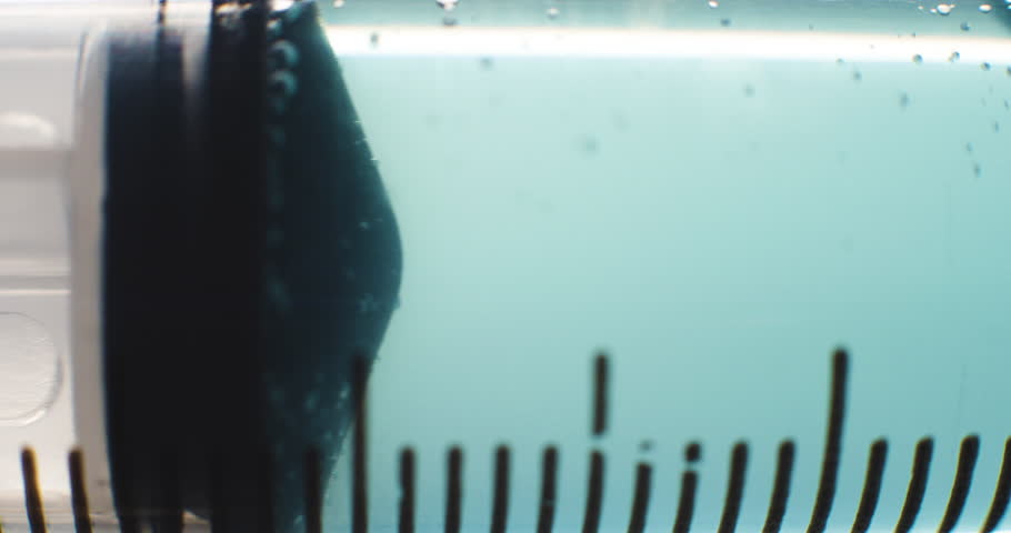 Syringe with Light Blue Liquid Passing Through