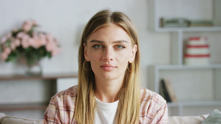 Woman is displaying a range of facial expressions, transitioning from a neutral expression to a joyful smile, showcasing subtle changes in her demeanor
