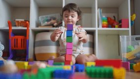 baby plays with toy blocks on the floor. development of fine motor skills in children concept. baby daughter girl builds a tower from lifestyle toy cubes indoors kindergarten - Powered by Shutterstock - Get 15% off with code: PIKWIZARD15