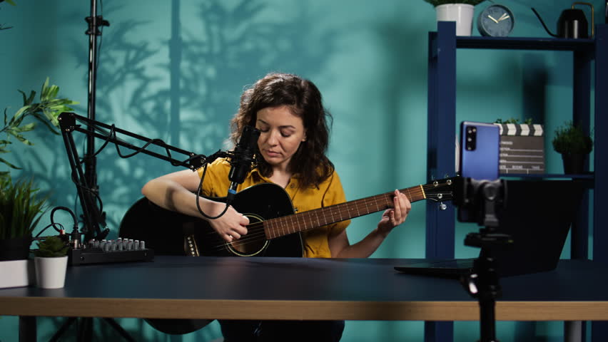 Talented woman playing music on guitar during livestream with audience online. Musician using musical instrument, having fun doing concert for fans producing entertaining songs, camera B