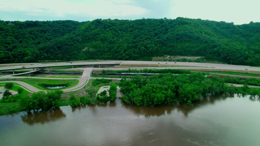 Aerial view of Interstate 90 crossing through a green landscape near La Crosse, Minnesota, with nearby river and parking area, and rest area.
