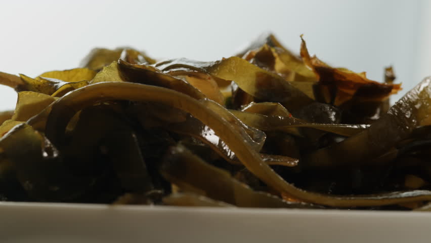 Japanese wakame seaweed chuka fermented food. Close-up on a detail of Hiyashi Wakame Chuka or seaweed salad or seaweed with sesame seeds on a plate. Top view. Seafood background. Health concept.