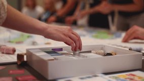 Process of playing tabletop board game on the table, fun with friends and family in room indoors, board game concept, company group of students adults play board games, roll the dice on a game map - Powered by Shutterstock - Get 15% off with code: PIKWIZARD15