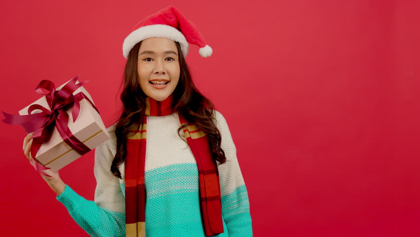 Happy smiling asian woman holding gift box over red background.
