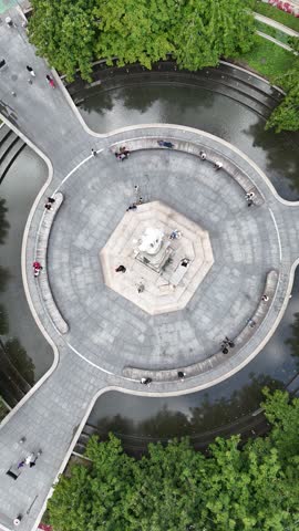 Drone pulling up and rising above the Columbus Monument in NYC, revealing the surrounding cityscape and traffic.