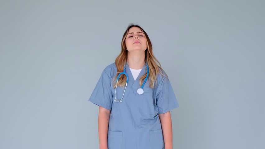 Unhappy Doctor Or Nurse Suffering From Headache Or Migraine On Gray Background