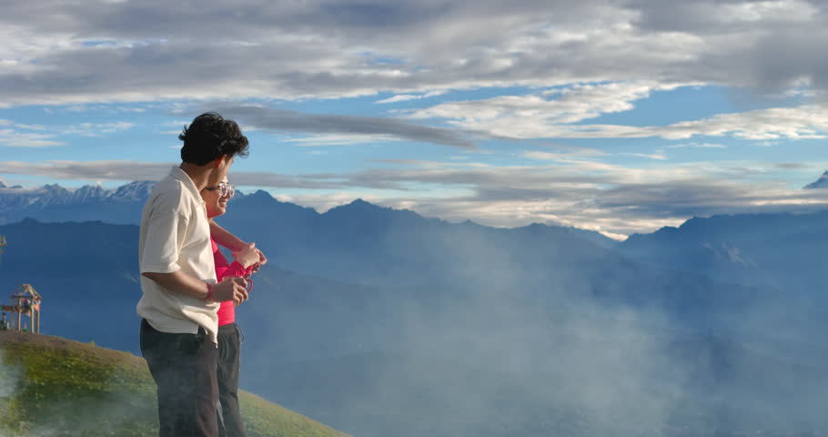 Drone shot captures romantic couple drinking tea as clouds pass by, touching them on Sailung Hill, Dolakha, Nepal enjoy nature