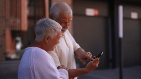 Closeup of cheerful elderly couple happily exploring new city streets, relying on smartphone for directions. Gray-haired senior male and female navigating unfamiliar city with smartphone navigation. - Powered by Shutterstock - Get 15% off with code: PIKWIZARD15