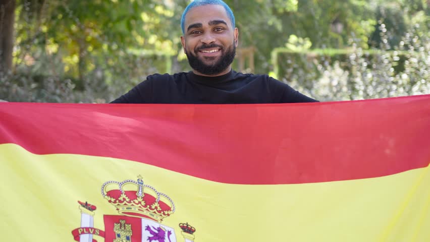 Black spanish citizen laughing and smiling happily and proudly holding a big spanish flag.MOV