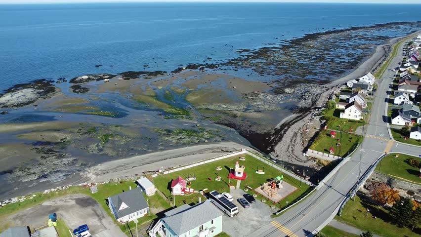 Aerial drone view of the mouth of the Rivière‑Blanche and the coastal shoreline of the Saint Lawrence River at low tide. The scene reveals exposed flats, winding water channels, and textured coastal terrain in Saint‑Ulric‑de‑Matane on the Gaspé Peninsula, Quebec, Canada, 2024.
