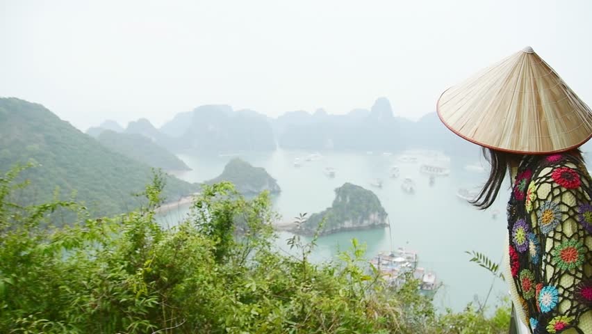 Caucasian happy young woman tourist stand on viewpoint enjoy famous Ha Long bay panorama with cruise boats