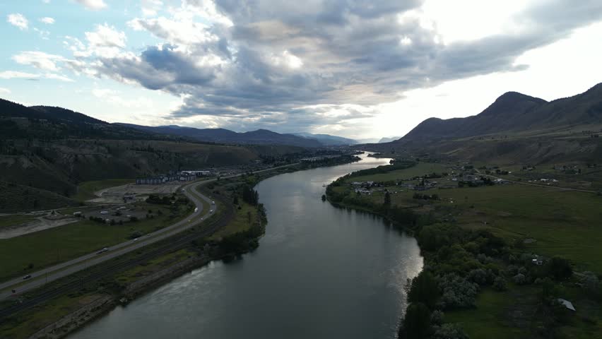 Aerial view of a river valley at sunset with mountains and clouds. British Columbia, Canada.