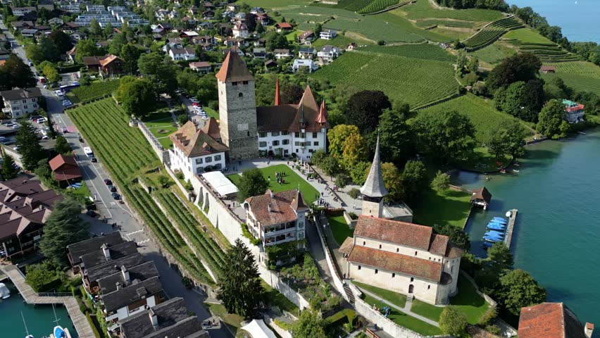Push out drone shot of the port and castle in Spiez with Thun lake in Canton of Bern in Switzerland.