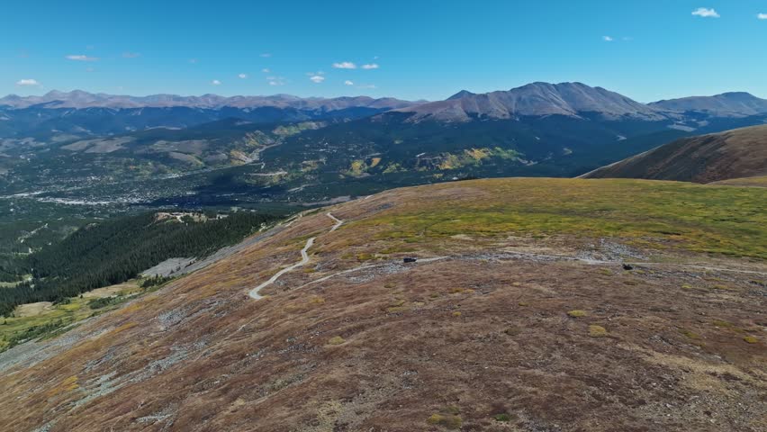 Panoramic aerial overview of car driving along Peak 10 trail Breckenridge Colorado with grand forest views behind
