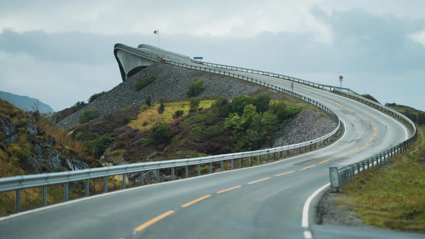 The smooth, curving lines of the Atlantic Road bridge climb dramatically over the landscape, meeting the sky.
