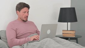 Coughing Middle Aged Man Feeling Unwell while Working on Laptop in Bed - Powered by Shutterstock - Get 15% off with code: PIKWIZARD15
