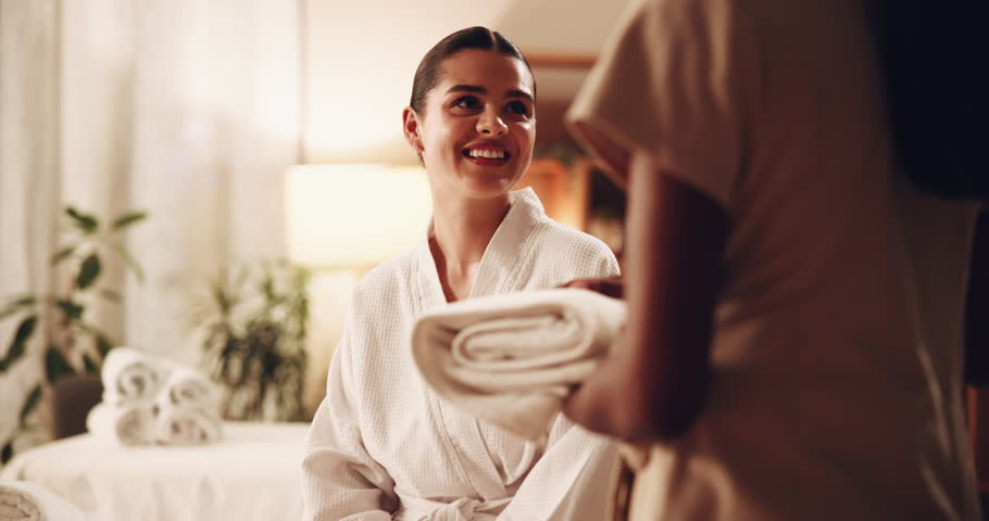 Towel, spa and woman on table, massage therapist and organised for hospitality and incense in beauty salon. Hotel, folded and resort for body care, people and retreat for treatment and aromatherapy