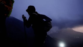 Hikers are using trekking poles and headlamps as they climb a mountain at night. The hikers silhouettes are illuminated against the twilight sky - Powered by Shutterstock - Get 15% off with code: PIKWIZARD15