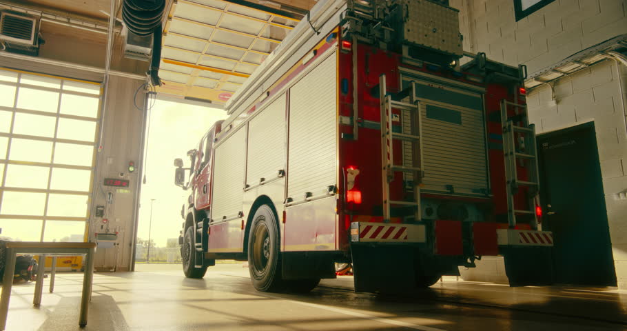 Fire Truck Exits the Fire Department, Highlighting the Urgency and Readiness of Firefighters Responding to an Emergency Call. Team Drive Off to Handle a Critical Situation. Warm Color Grade