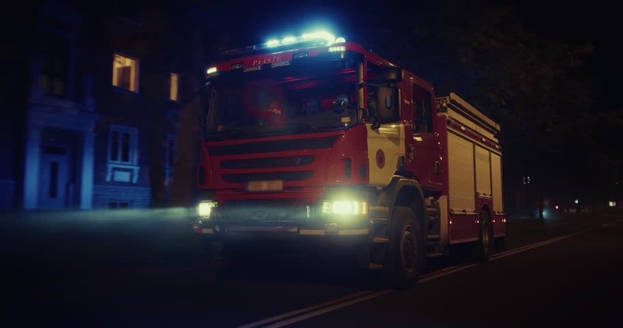 Night is Lit Up by the Flashing Emergency Lights of a Fire Truck, Rolling Through the Dark Streets in Response to an Incident. Vehicle Speeds Through the City on a Mission to Save Lives