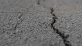 Close-up of asphalt texture with deep cracks. Part of the video is out of focus. Moving forward. Dry old cracked asphalt surface. High quality 4k footage - Powered by Shutterstock - Get 15% off with code: PIKWIZARD15