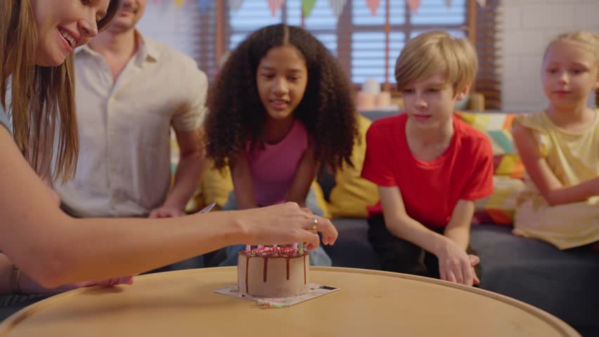 Multiracial family having a birthday party for young daughter in house. Attractive parents and children feeling happy and relax, enjoy celebrating birthday party during holiday in living room at home.
