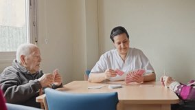 Nurse plays cards with a senior man in a nursing home, showcasing a joyful interaction in slow motion - Powered by Shutterstock - Get 15% off with code: PIKWIZARD15
