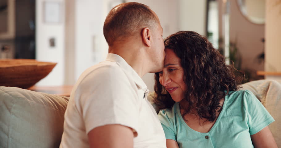 Kiss, love and relax with mature couple on sofa for bonding, romance and happiness. Care, support and marriage with man and woman in living room of home for relationship, cuddle and hug together