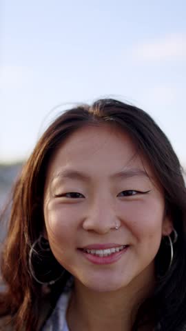 Positive Asian woman looking at camera and taking a photograph with an analog camera.