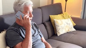 A mature man enjoys his free time at home while making a phone call from the comfort of his cozy sofa, demonstrating the importance of personal connection in the senior lifestyle - Powered by Shutterstock - Get 15% off with code: PIKWIZARD15