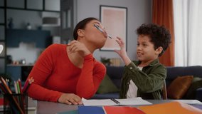 Happy African American family having fun funny play woman mom help with homework little son boy child kid together studying home education mother hold pen with lips pretend to have mustache laugh - Powered by Shutterstock - Get 15% off with code: PIKWIZARD15