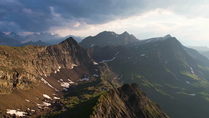 Aerial of alpine mountains in Switzerland in the Grindelwald valley at sunset. Dramatic storm clouds over high peaks