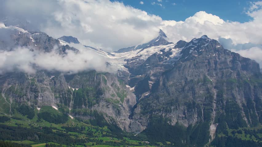 Cinematic drone fly over snow mountain and green meadows of tourist resort Grindelwald valley in Switzerland Bernese Alps. Travel and healthy lifestyle
