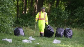 Man cleaning up the park, putting trash in a garbage bag. Environmental protection. Picking up garbage plastic for cleaning. Keeping garbage plastic into black bag for trash. Pollution and recycling. - Powered by Shutterstock - Get 15% off with code: PIKWIZARD15
