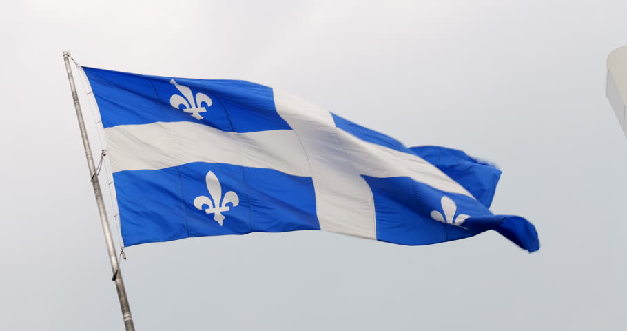 The Quebec provincial flag waves in the wind, displaying its blue field and white fleurs-de-lis, symbolizing Quebec