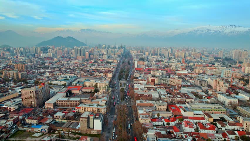 Fly over the Alameda Avenue in Santiago de Chile, with the Andes Mountains in the background, sunset with pollution.