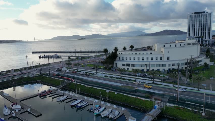 A stunning drone push-in shot towards the waterfront at Treasure Isle Marina, Yerba Buena Island, CA. The scene captures the marina, shoreline, and boats against a scenic coastal backdrop.