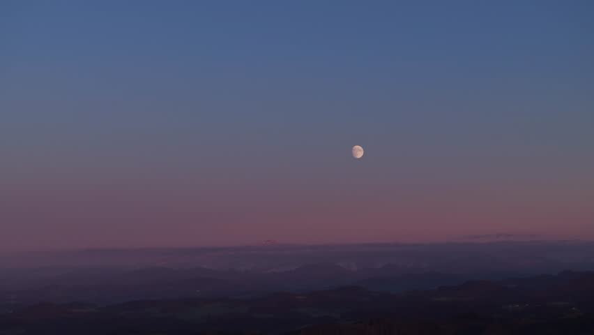 Autumn landscape with mountains in the background and fresh snow on the mountain range. Full moon on the mountain peak with sunset. The top of the mountain rises out of the fog.Wide shot
